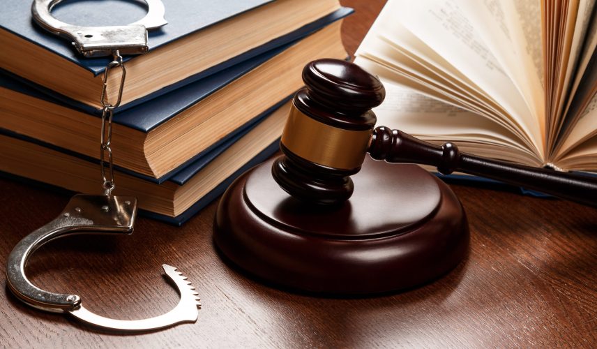 Gavel, books and handcuffs on wooden table