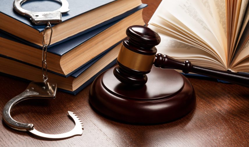 Gavel, books and handcuffs on wooden table